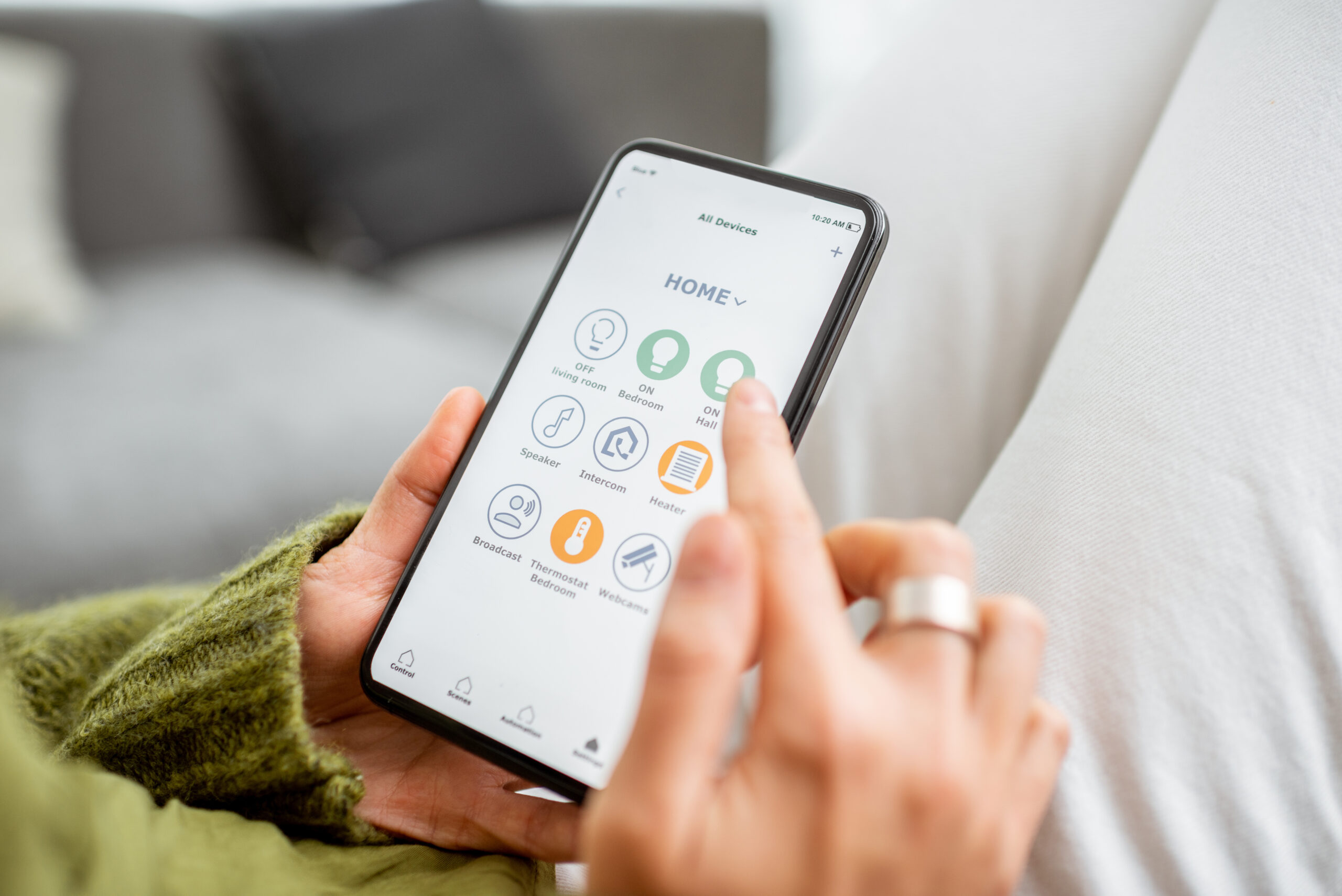 Junge Frau, die ihr Zuhause mit einem Smartphone steuert. Konzept eines Smart Homes und einer mobilen Anwendung zur Verwaltung smarter Geräte zu Hause.