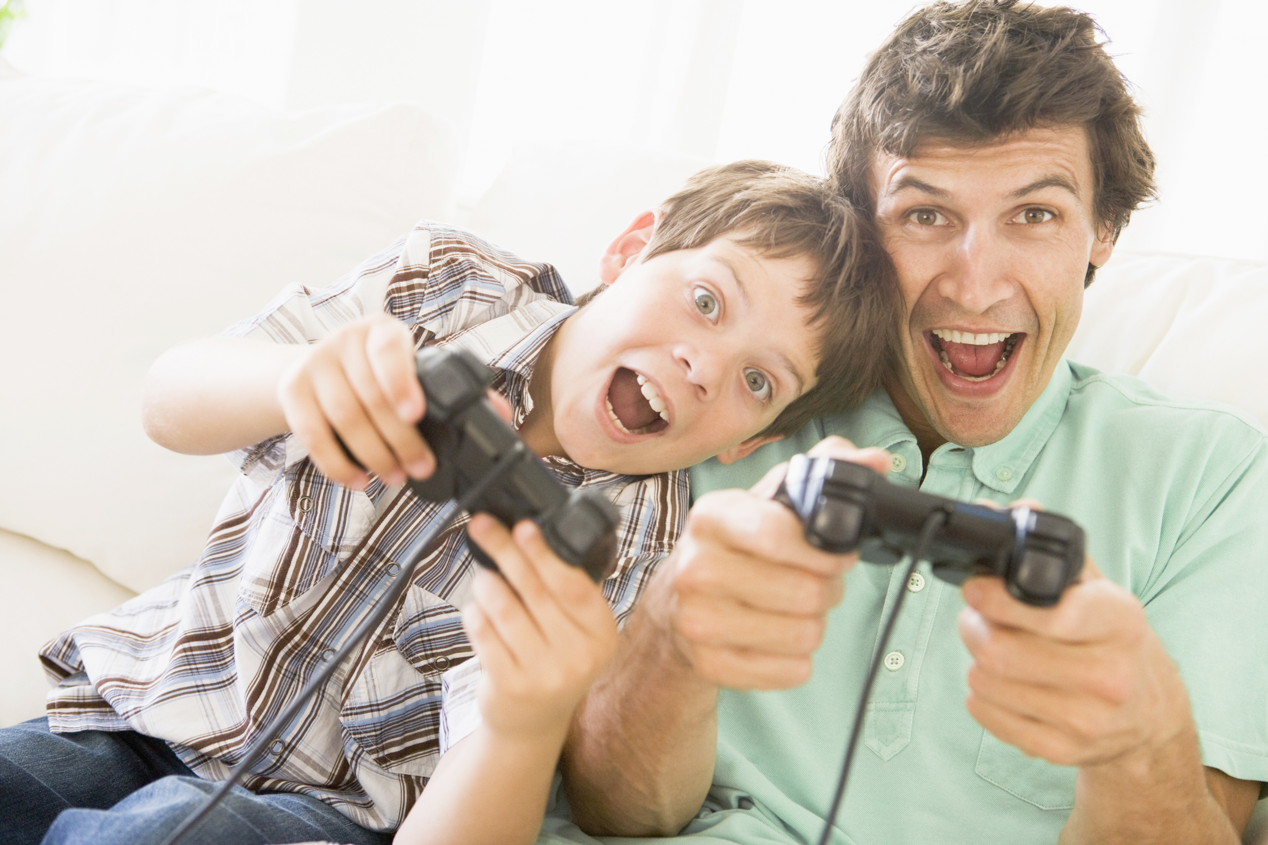 Mann und kleiner Junge mit Videospiel-Controllern lächeln